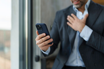 A focused male executive in a tailored suit interacts with a smartphone, displaying modern...