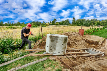 Worker pushes concrete ring along roller deck using crowbar lever.