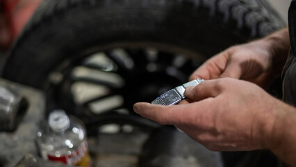 A mechanic attaches balancing weights to a wheel. 