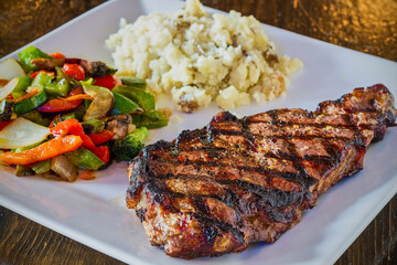 grilled strip steak served with mashed potatoes and sautéed veggies