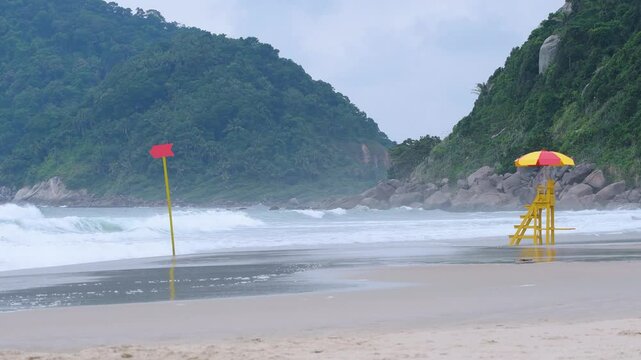 Rough sea at the Tombo beach of Guaruja - SP, Brazil. Beach of the coast of S&atilde;o Paulo state. View to the beach, the lifeguard chair and some mountains on background.