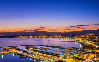 Cityscape of roses, spain, with its harbor and boats reflecting in the sea, illuminated by the warm...