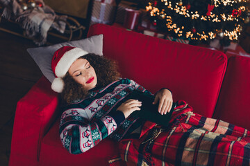 Portrait of nice young woman sleep sofa book wear sweater new year xmas garland lights flat indoors