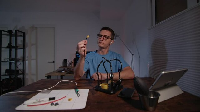 A man in glasses is Soldering power connectors and electronic parts in the workshop