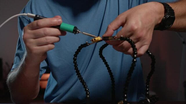 Mans hands is Soldering Wires and Connectors on a third hand support