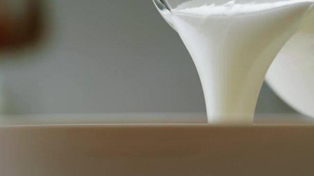 Pouring kefir yogurt into glass cup close-up. Glass with kefir or milk, lactic acid product dairy products concept. Drinking fresh lactose free in morning.