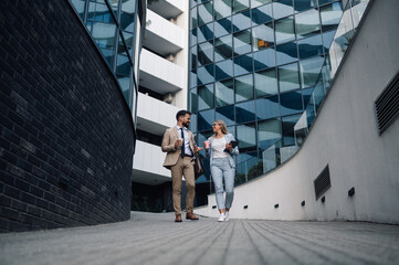 Business people walking and talking in front of modern office building