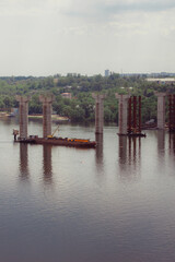 Naklejka premium Concrete bridge over the river. Complex technical projects. A large architectural structure under construction. Temporary iron piles for the construction of columns. Large industrial equipment.