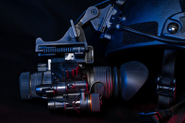 Night vision monocular mounted on a tactical helmet, close-up photo in the dark.