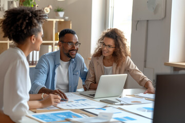 Professionals in a bright office analyze charts and data on laptops, highlighting teamwork, attention to detail, and strategic planning to boost productivity. Concept: collaborative workspace
