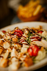 A rich Caesar salad served on a white plate, topped with creamy dressing, parmesan, and freshly baked croutons, garnished with fresh vegetables. A perfect choice for lovers of healthy and delicious fo