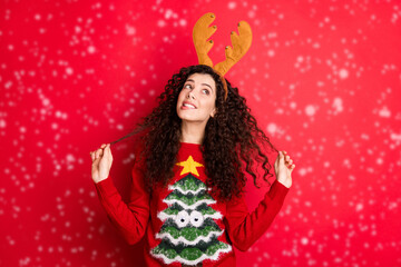 Photo of funny curly lady dreaming x-mas would bring peace and love to all people on earth looking empty space wear head horns pullover isolated red color background