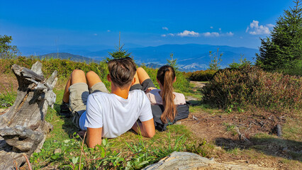 A couple of boyfriend and girlfriend are resting and looking into the distance in the mountains on Barania Gora
