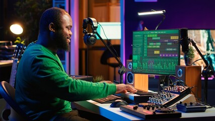 Audio engineer recording and producing new tunes on professional pc software, using mixing console...