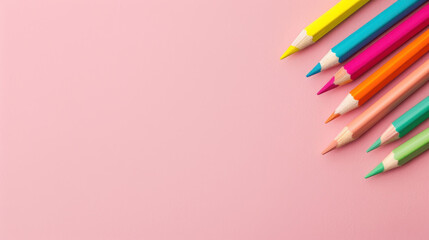 Fototapeta premium Vibrant colored pencils spill across a pastel pink ad backdrop, perfect for promoting art supplies and creativity.