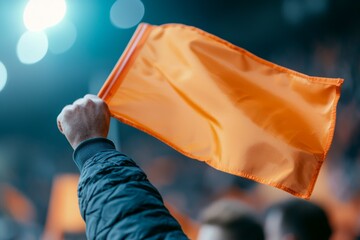 A person is holding an orange flag in a crowd