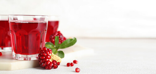 Glasses of fresh pomegranate juice on light background