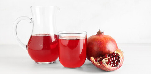 Jug and glass of fresh pomegranate juice on white wooden table