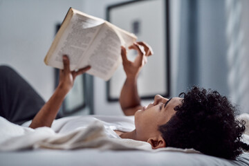 Book, reading and relax with teen on bed in home for weekend education, literature or study. Hobby,...