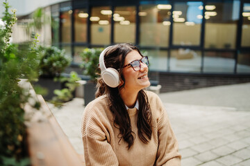 Fototapeta premium Young caucasian woman listening to music or audiobook outdoors 