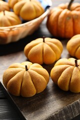 Tasty pumpkin shaped buns on wooden table, closeup