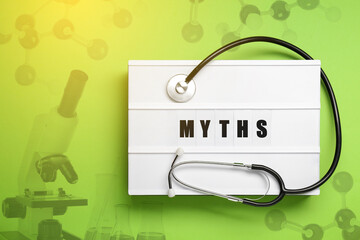 Medical myths. Light box with word and stethoscope. Yellowish green background with molecular model...