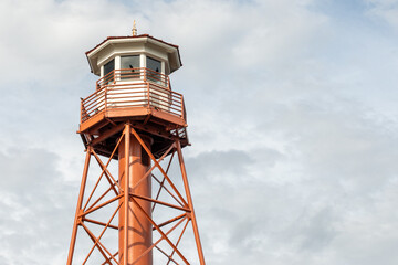 Fire lookout tower high in the sky with a cloudy sky background. The building has many steps...