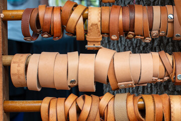 Racks and rows of brown leather wrist straps. The handcrafted traditional accessory bracelets have different tan leather buckskin wristbands. The round classic crafts have patterns and snaps. 