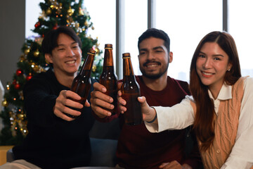 A group of diverse friends celebrates Christmas at home with alcoholic drinks. There is celebration and festivity, and different hands hold glasses with drinks, champagne bottles, wine, and cocktails.