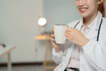 Female medical professional enjoying a coffee break, holding a mug in her hands, showcasing a moment of relaxation amidst a busy workday in a hospital or clinic environment - Powered by Adobe