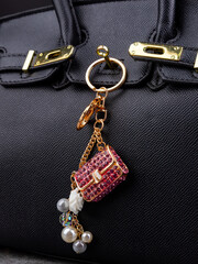 Close up of bright metal keychain with rhinestones in the shape of a handbag on a white bag
