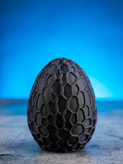 Close-up of a plastic egg model with ornament on a blue background