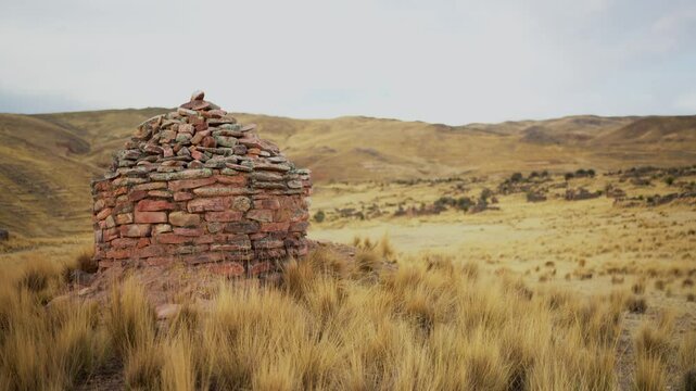 Inca chullpas in the Andes mountain range at sunset with a cloudy sky and surrounded by vegetation