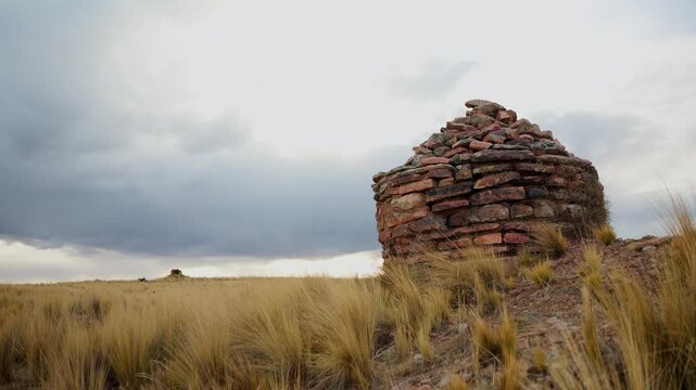 Inca chullpas in the Andes mountain range at sunset with a cloudy sky and surrounded by vegetation