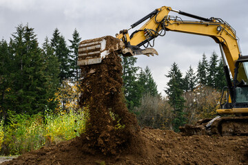 Beginning of new home construction, excavator digging dirt out for house foundation on a stormy fall day
