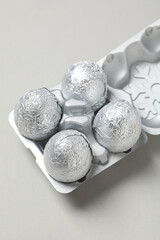 Foil balls in silver case on light gray background, close up
