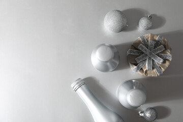 Silver bottles, gift box and Christmas balls on gray background, space for text