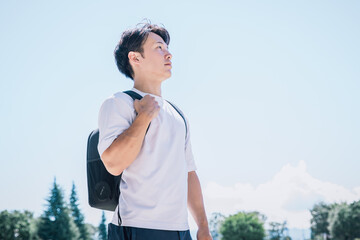 青空の下上を向いて歩く男性
A man walking looking upwards under the blue sky