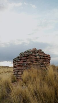 Inca chullpas in the Andes mountain range at sunset with a cloudy sky and surrounded by vegetation