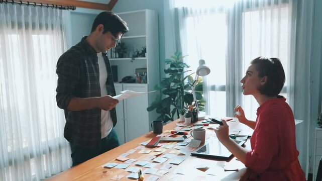 Top view of smart designer holding color palette while project manager looking at design and choosing color for program. Professional businesswoman taking a note while design creative logo. Symposium.