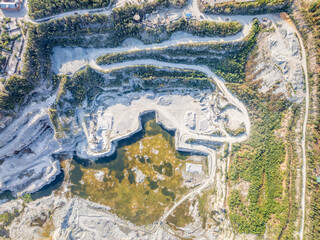 Stone quarry in the forest. Flying over the summer mixed forest during sunset. The surroundings of Yekaterinburg. Ural, Russia, Aerial View