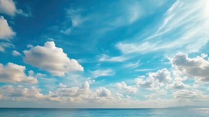 Obraz premium Expansive blue sky with scattered clouds over calm ocean, creating serene and peaceful atmosphere. Perfect for relaxation and inspiration