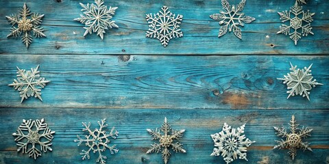 Silver snowflakes arranged on a weathered teal blue wood background with rustic charm and winter ambiance.