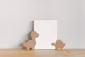 Blank picture poster frame template with dinosaur toys on the wooden table. Mock up poster frame, canvas template. © Kolomiiets Viktoriia