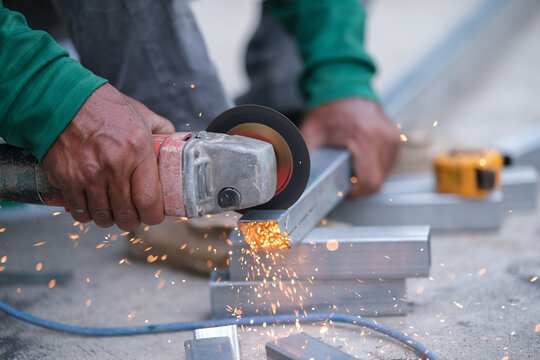 Using a Abrasive Cutoff Machine or chop saw on the floor to cut a piece of steel square tube. - Powered by Adobe