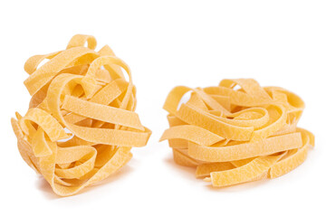 Two Classic Italian Raw Egg Fettuccine - Isolated on White Background. Dry Twisted Uncooked Pasta. Italian Culture and Cuisine. Raw Golden Macaroni Pattern - Isolation