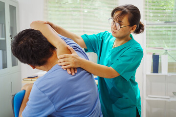 Obraz premium A female doctor performs physical therapy on a male patient in the hospital, using techniques like pulling, massaging, and compressing to rehabilitate injuries, relieve pain,restore daily functional