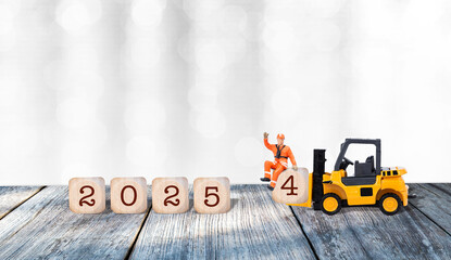 Happy New year 2025 on wooden cube with miniature worker and forklift truck on wooden floor over...