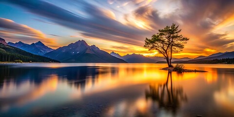 Fototapeta premium Solitary Tree Silhouette Reflects on Calm Lake Waters During a Serene Sunset Over Majestic Mountain Range