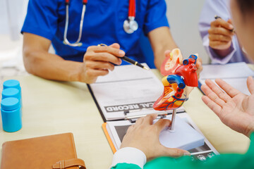 Doctors meet at a hospital desk to discuss a patient’s heart health, including conditions like...